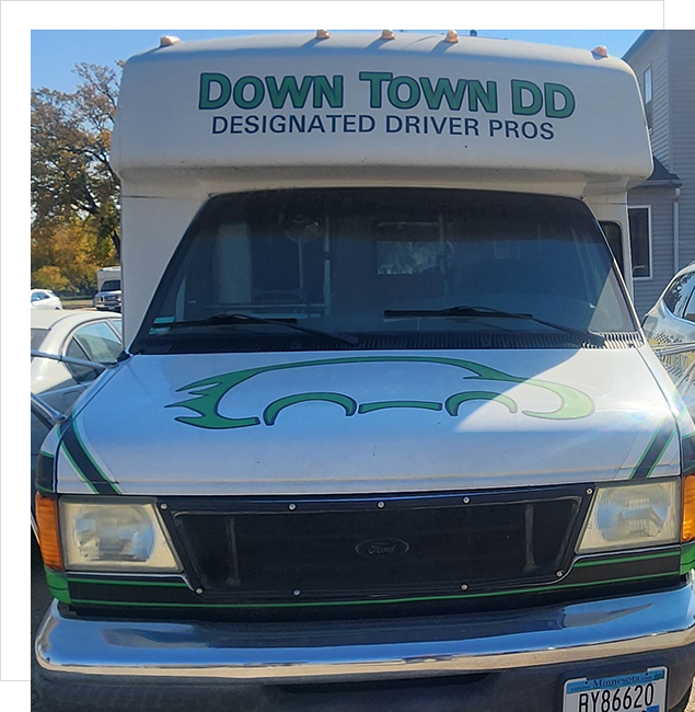 A white truck with green lettering parked in front of other vehicles.